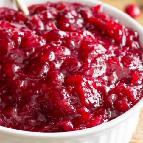 Close-up of bright red cranberry sauce in a white bowl.