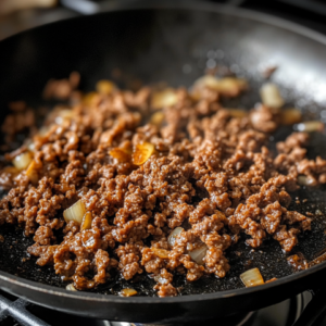 Ground beef cooking with garlic and ginger in a skillet